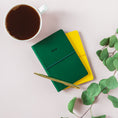 Load image into Gallery viewer, a green and yellow notebook next to a cup of coffee