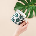 Load image into Gallery viewer, a person holding a cup with a green leaf pattern on it