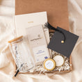 Load image into Gallery viewer, a gift box containing a candle, candle holder, and a graduation cap