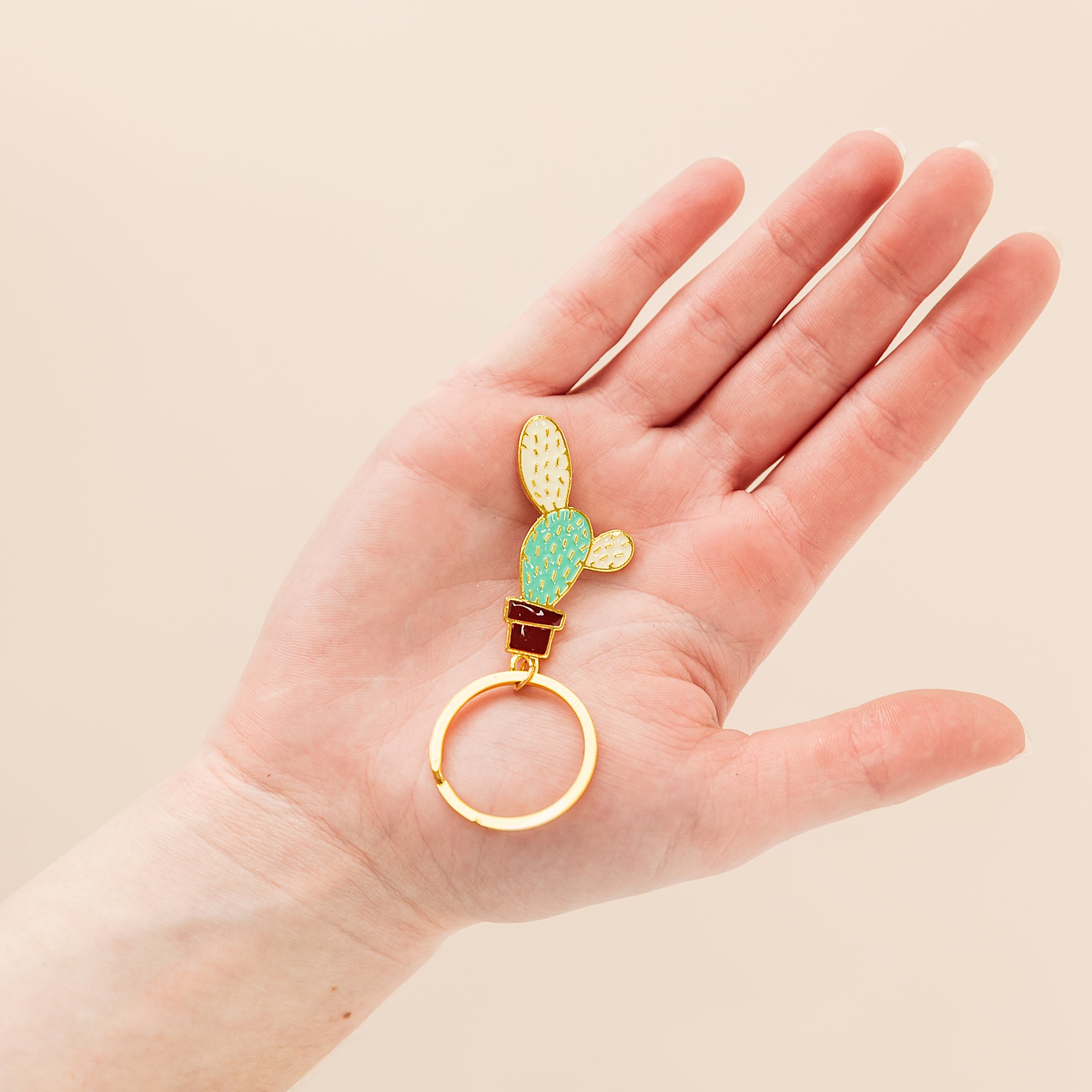 a person's hand holding a ring with a cactus on it