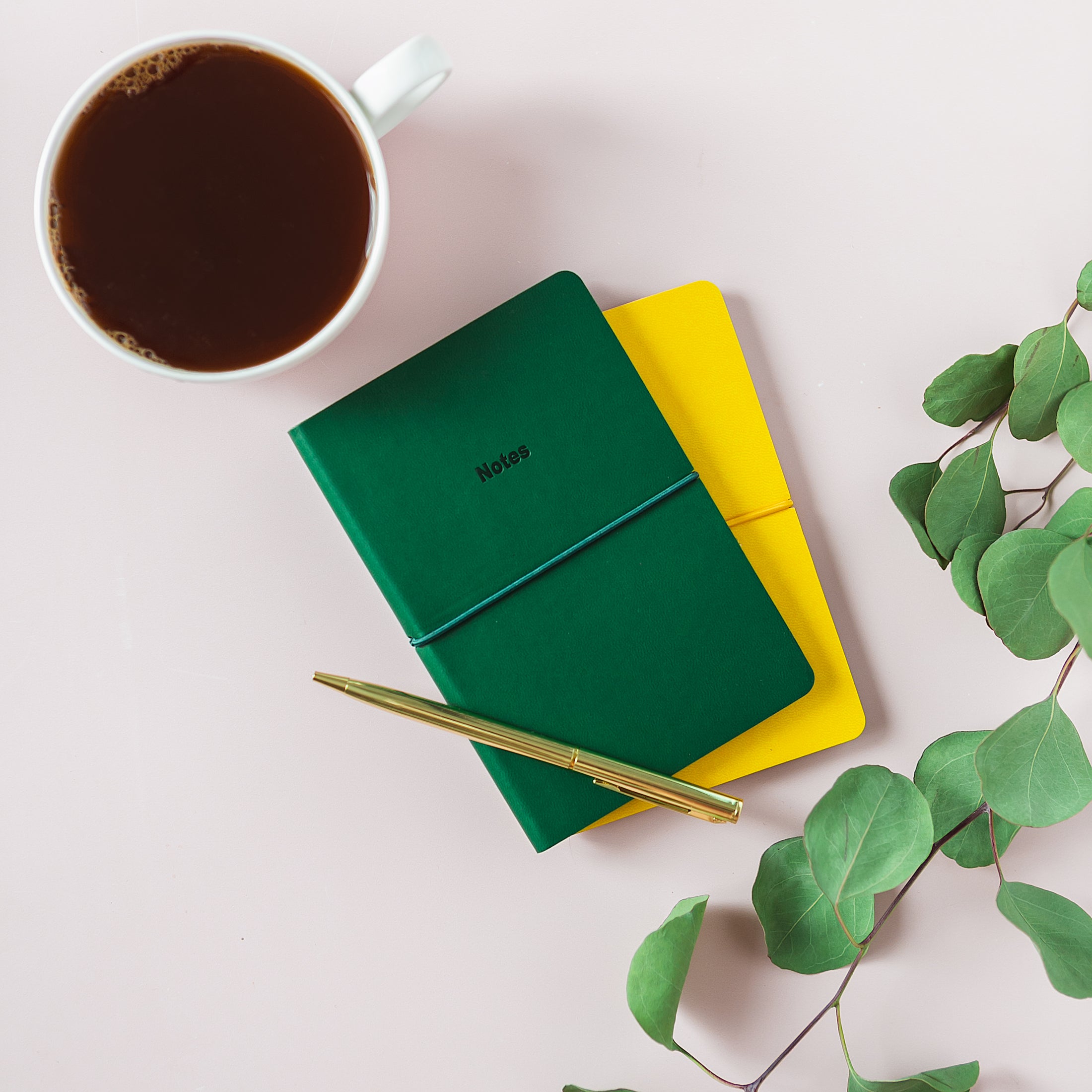 a green and yellow notebook next to a cup of coffee