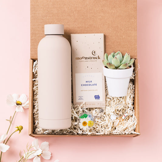 a box containing a bottle of water, a bottle of milk, and a plant
