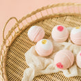 Load image into Gallery viewer, a basket filled with pink and white bath bombs
