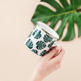 Load image into Gallery viewer, a person holding a cup with a green leaf pattern on it
