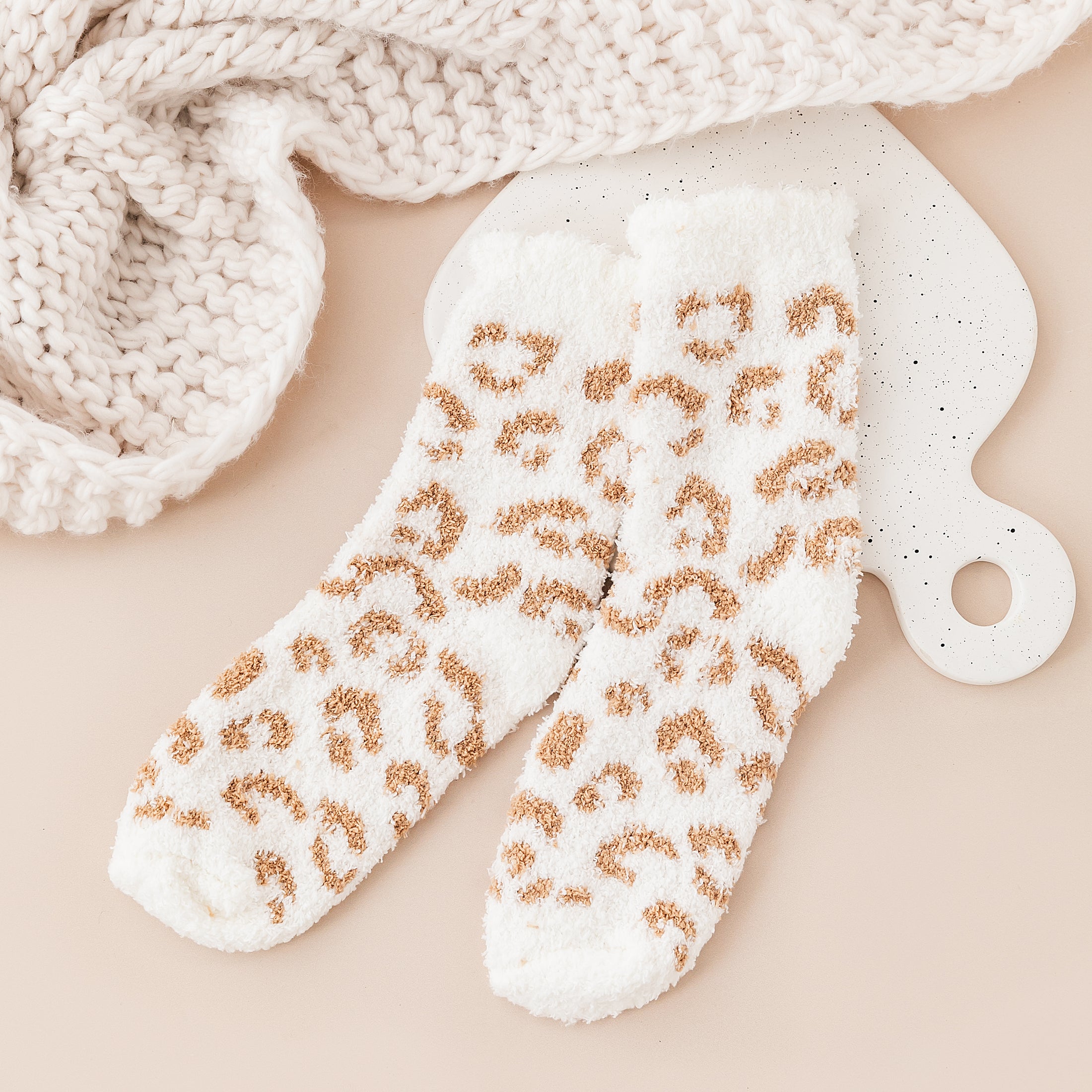 a pair of white and gold leopard print mitts next to a white knitted