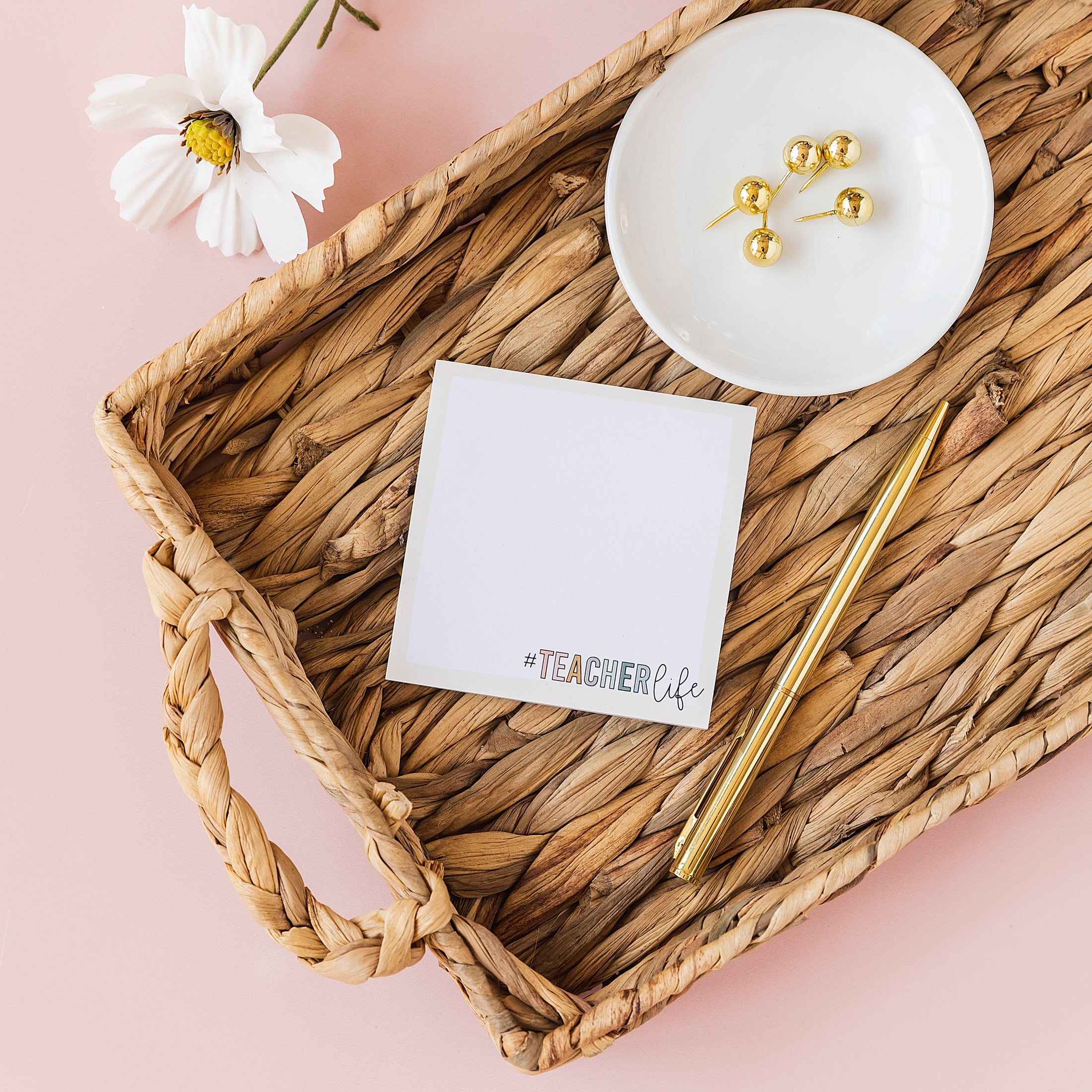 a basket with a notepad, pen, and flower on it