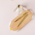 Load image into Gallery viewer, a wooden cutting board topped with two gold colored pens
