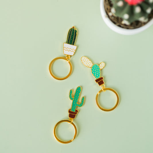 a pair of gold - plated metal cactus and cactus keychains