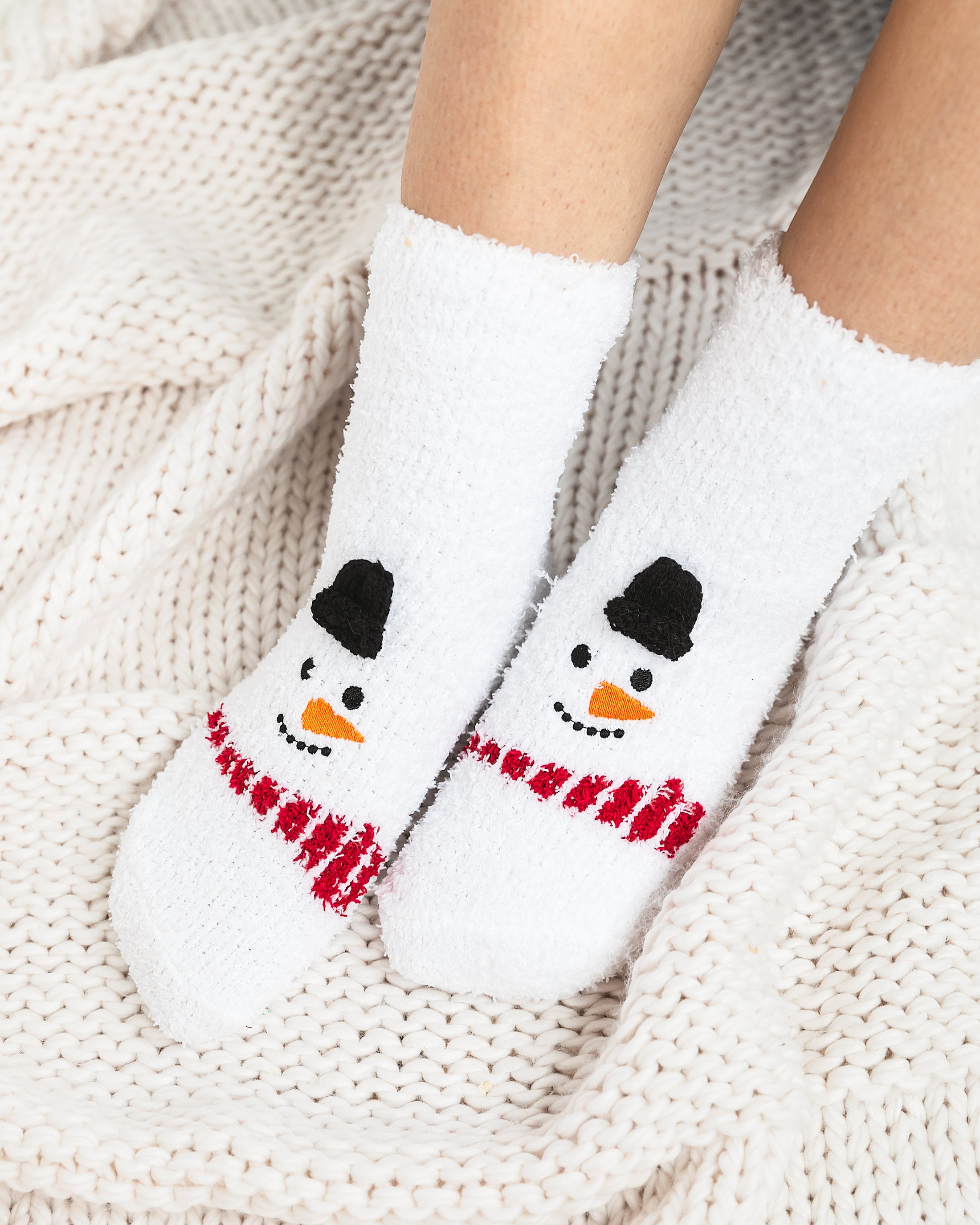 a pair of snowman socks sitting on top of a white blanket