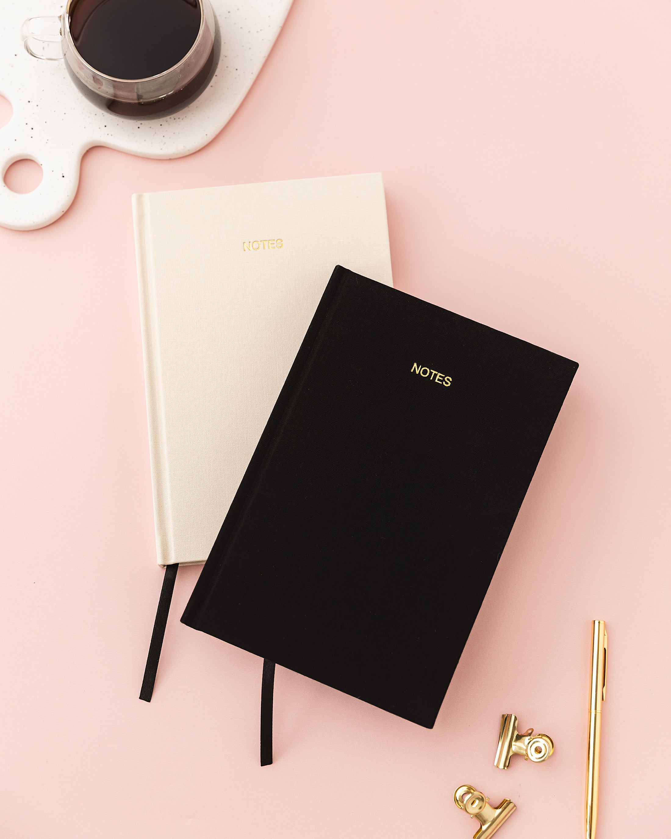 a black and white notebook sitting on top of a desk next to a cup of